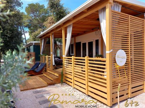 a wooden cabin with a porch and a deck at PAMARA Mobile Home in Biograd na Moru