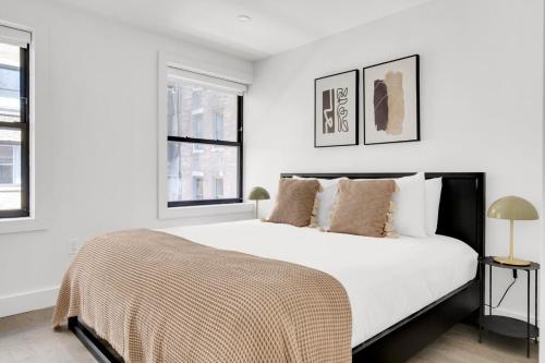 ein weißes Schlafzimmer mit einem großen Bett und zwei Fenstern in der Unterkunft UWS 2BR w WD Deck nr Central Park NYC-773 in New York