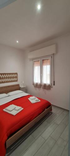La Siciliana Trapani Apartment في تراباني: غرفة نوم مع سرير مع بطانية حمراء و نافذتين