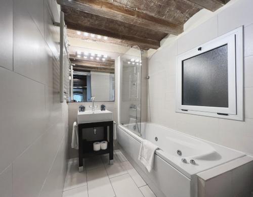 a bathroom with a tub and a sink and a tv at Stay U-nique Apartments Plaça Universitat in Barcelona