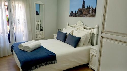 a white bedroom with a large white bed with blue pillows at Narciso Tomé en San justo 4 in Toledo