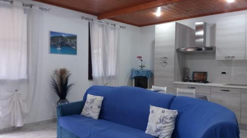 a blue couch in a living room with a kitchen at Casa Marcella in Dorgali