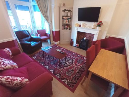 a living room with a red couch and a fireplace at Brackenhurst Guest House in Skegness