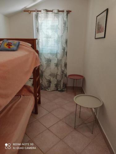 a bedroom with a bed and a table and a window at Apartments Nino in Štivan