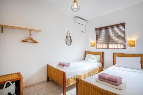 een kamer met 2 bedden, een tafel en een raam bij TUK Tropical Boutique Resort Jan Thiel in Willemstad
