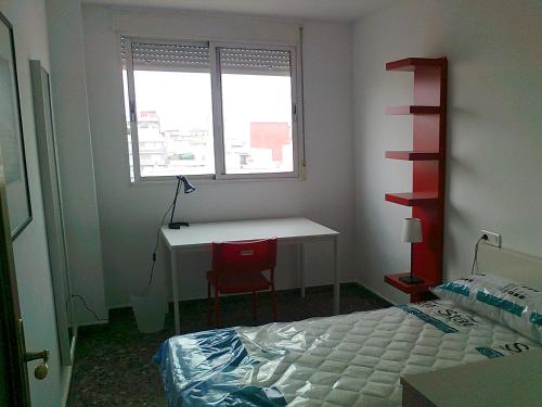 a bedroom with a bed and a desk and a window at PISO CON VISTAS in Burjasot