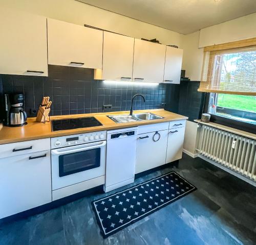 een keuken met witte kasten en een wastafel bij Gemütliche Ferienwohnung für 4 Personen in Baumholder