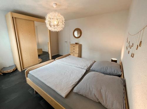 een slaapkamer met een groot bed en een kroonluchter bij Gemütliche Ferienwohnung für 4 Personen in Baumholder