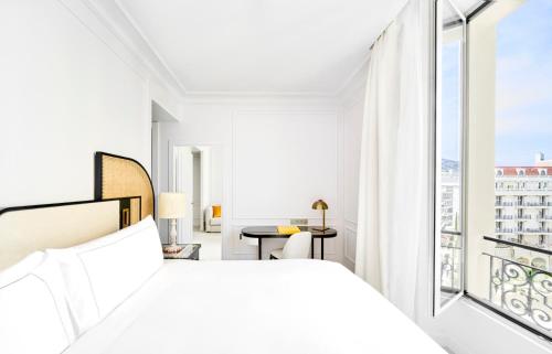 Carlton Cannes, a Regent Hotel في كان: غرفة نوم بيضاء مع سرير وشرفة