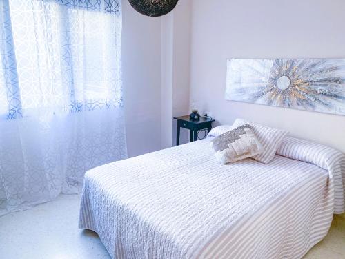a white bedroom with a bed and a window at El rinconcito de la Isla in San Fernando