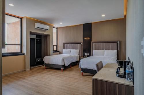 a hotel room with two beds and a television at Hotel Kavia Premium - Paseo Montejo in Mérida