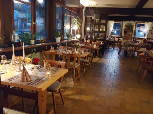a restaurant with wooden tables and chairs and windows at Kräuterhex' Reutin in Alpirsbach