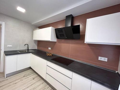 a kitchen with white cabinets and a black counter top at ACENI in Ciudad Real