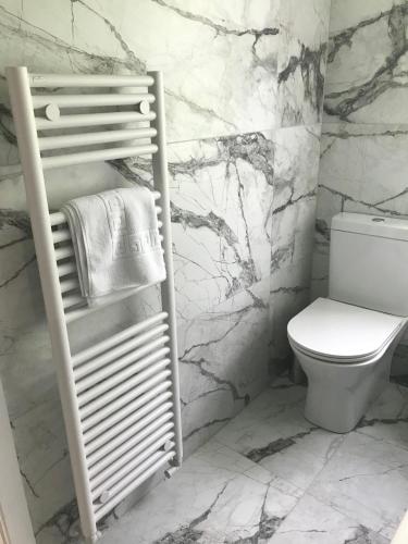 a bathroom with a toilet and a towel rack at La Suisse Serviced Apartments in Manchester