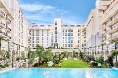 une image de la cour d'un bâtiment avec piscine dans l'établissement Carlton Cannes, a Regent Hotel, à Cannes