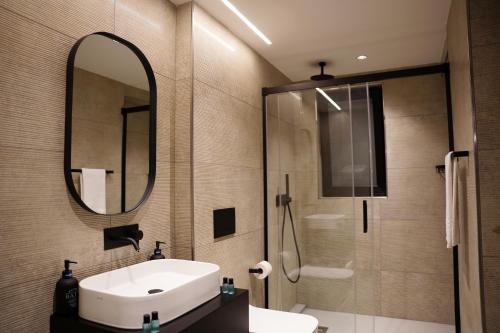 a bathroom with a sink and a mirror and a shower at The Londoner Hotel Sliema in Sliema