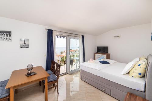 a bedroom with a bed and a table and a balcony at Apartments Tilda in Brist