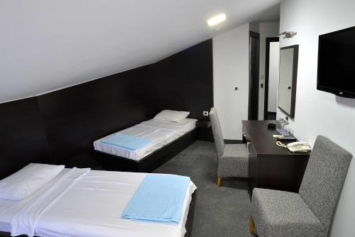 a hotel room with two beds and a desk and a television at Hotel Golf in Kruševac