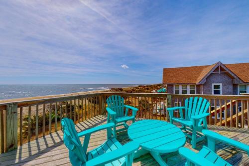 three blue chairs and a table on a deck with the ocean at Stellar Vista in Avon