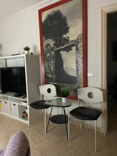 uma sala de estar com duas cadeiras e uma mesa e uma televisão em Apartamento Casa Barbara em Puerto de la Cruz