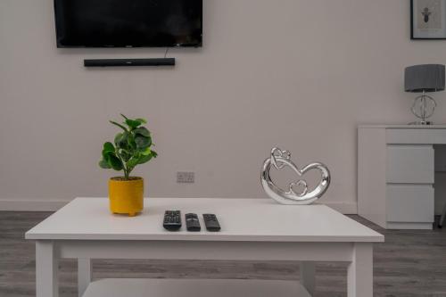 a white table with a potted plant and a tv at Spacious 4 Bedroom Apartment in Coventry