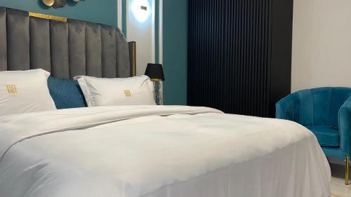 a bedroom with a white bed and a blue chair at Suna' a Home Bonapriso in Douala