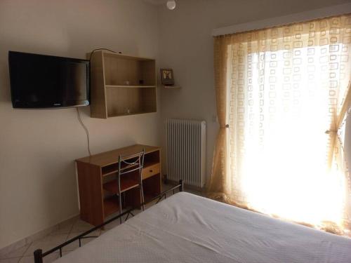 a bedroom with a bed and a tv and a window at Stefkas apartment1 in Patra