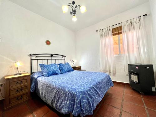 1 dormitorio con 1 cama con edredón azul y ventana en Duplex con bonita vista al Mar, Wifi y barbacoa en El Hierro, en Erese