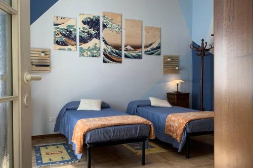 2 camas en una habitación con pinturas en la pared en La Casa del Nonno, en Omegna
