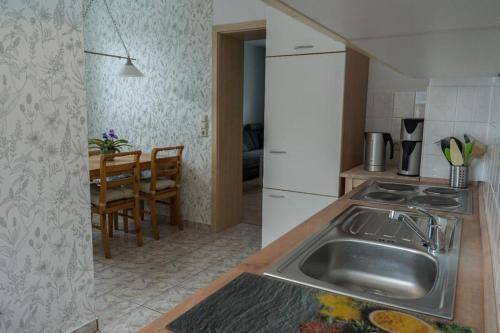 una cucina con lavandino e tavolo con sedie di Ferienwohnung Otto a Klingenthal