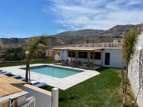 a villa with a swimming pool and a house at Grande Blue Suites with private bay in Archangelos