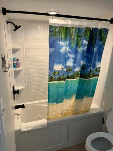 a bathroom with a shower curtain with a beach at Breakers Resort in Myrtle Beach