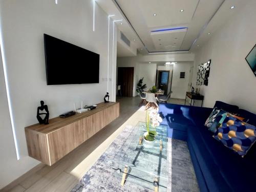 sala de estar con sofá azul y TV de pantalla plana en Relax Apto Pool and Golf View in Hard Rock Golf en Punta Cana