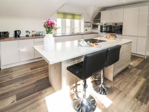 a kitchen with white cabinets and a large island with a black stool at Butterchurn Apartment in Newcastle upon Tyne