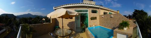 a house with a swimming pool and an umbrella at Pousada da Gigoia - Barra da Tijuca in Rio de Janeiro