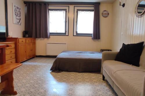 ein Schlafzimmer mit einem Bett, einem Sofa und Fenstern in der Unterkunft Studio spacieux au pied des pistes sans vue in Orcières