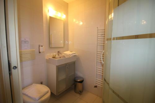 a bathroom with a sink and a toilet and a mirror at Auberge de la Couronne in Lablachère