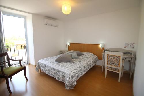 a bedroom with a bed and a desk and a window at Auberge de la Couronne in Lablachère