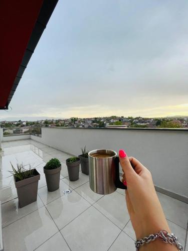 a person taking a picture of a cup on a balcony at Bojana Apartment Penthouse in Negotino