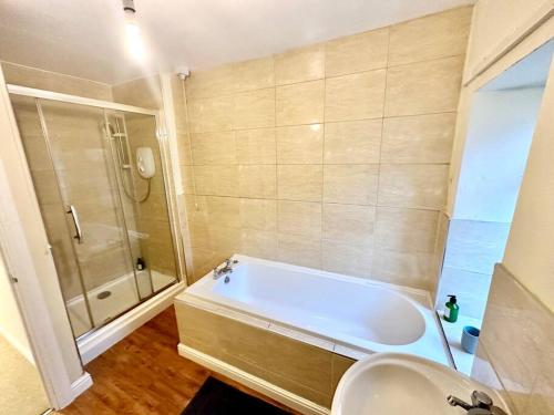 een badkamer met een bad, een douche en een wastafel bij Cottage,Cinema Room,Log Burner in Blaenavon