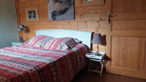 a bedroom with a bed and a table with a lamp at Chalet Les Vosgiennes in Le Valtin