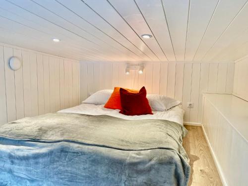 a bedroom with a bed with two red pillows on it at Orres Guesthouse Stenhamra, Ekerö in Stenhamra