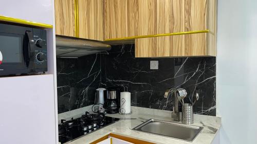 a kitchen counter with a sink and a microwave at Suna' a Home Bonapriso in Douala