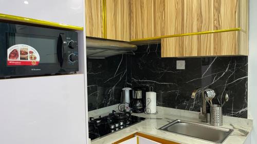 a kitchen with a sink and a microwave at Suna' a Home Bonapriso in Douala