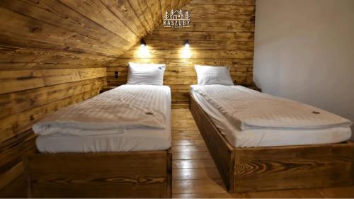 2 Einzelbetten in einem Zimmer mit Holzwänden in der Unterkunft Kaszuby Camp in Barkocin