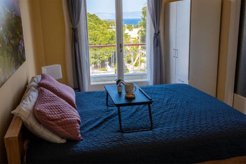 a bedroom with a bed with a table and a window at Zoumperi Nea Makri 4-5 guest apt big balconies 5 min to beach in Nea Makri