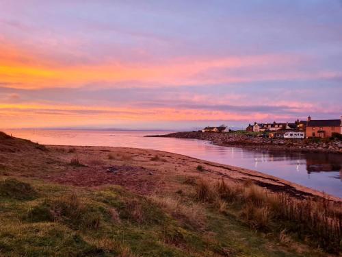 a sunset over a body of water with houses and buildings at Brora Pods in Brora