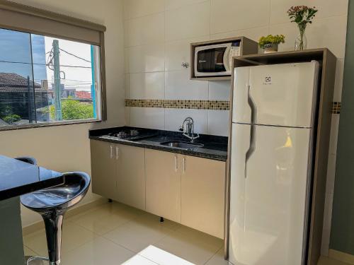 a kitchen with a refrigerator and a sink and a window at Mangata Loft - Requinte e Conforto para Lazer ou Trabalho in Itanhaém