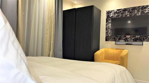 a bedroom with a bed and a tv and a chair at Suna' a Home Bonapriso in Douala