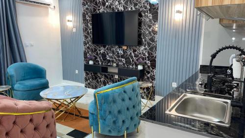 a living room with a sink and a tv on a wall at Suna' a Home Bonapriso in Douala